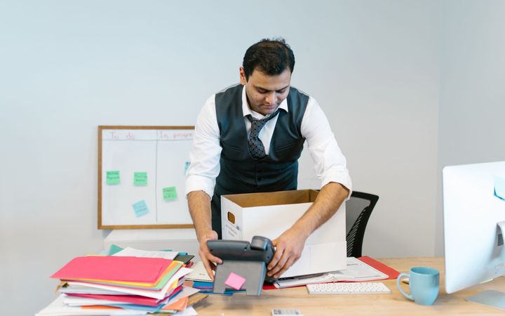 Beschriftete Umzugskartons und Bürostühle in einem leergeräumten Büro