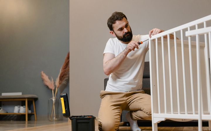 Handwerker montiert mit Akkuschrauber einen Schrank in einer leeren Wohnung