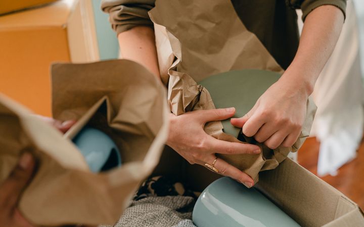 Gläser werden einzeln in Papier eingewickelt und in einen Umzugskarton gepackt